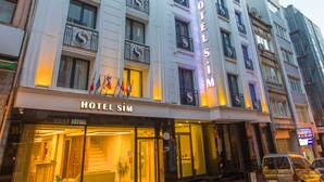 A multi-story hotel with balconies, a prominent sign reading "HOTEL SIM," and a well-lit entrance. - Sim Hotel (Istanbul)