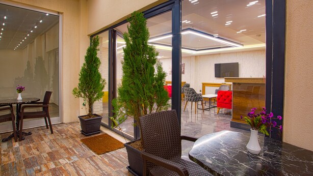 A modern indoor space with a glass door leading to a bright room, a seating area with a table and chairs, and a potted plant. - Sim Hotel (Istanbul)