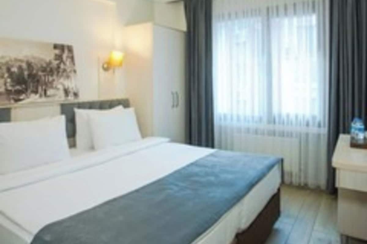 Una camera d'albergo con un letto, una scrivania e una finestra con tende.