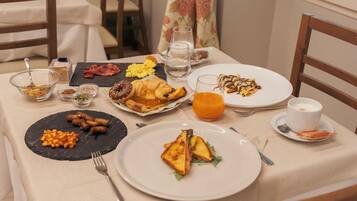 A breakfast table with various dishes including eggs, bacon, toast, and a croissant.