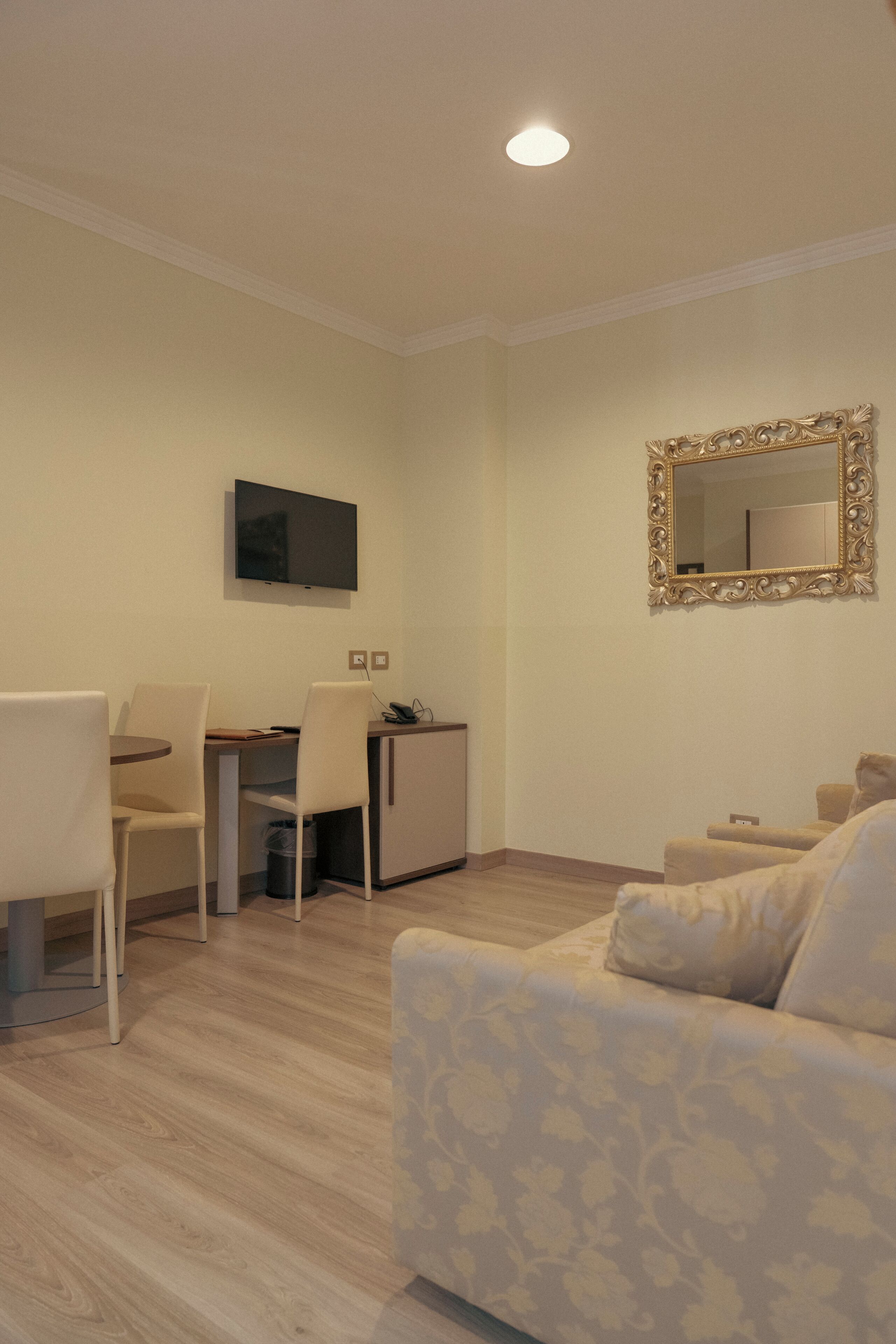 A compact living space with a dining area, a sofa, a TV, and a mirror.