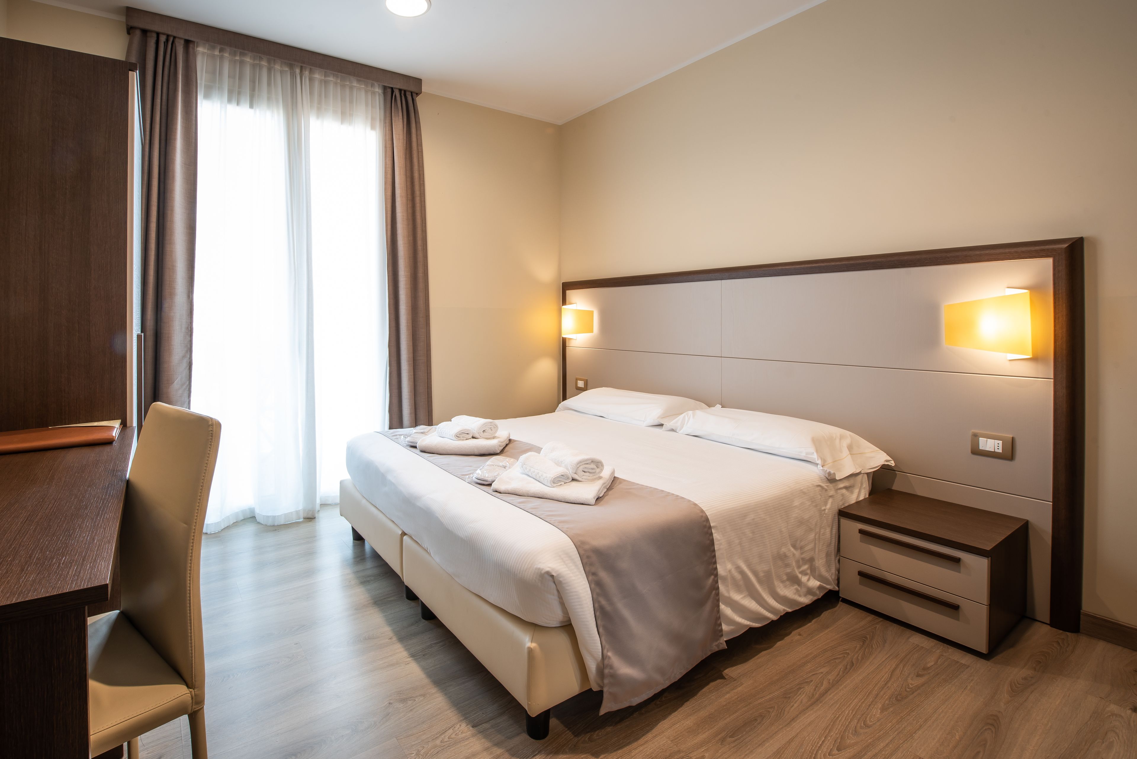 Une chambre d’hôtel comprenant un lit, des tables de chevet, un bureau et une chaise.