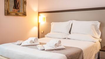 A hotel room with a neatly made bed, white linens, and a painting on the wall.