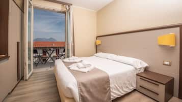 Una habitación de hotel con cama, mesita de noche y vistas al exterior.