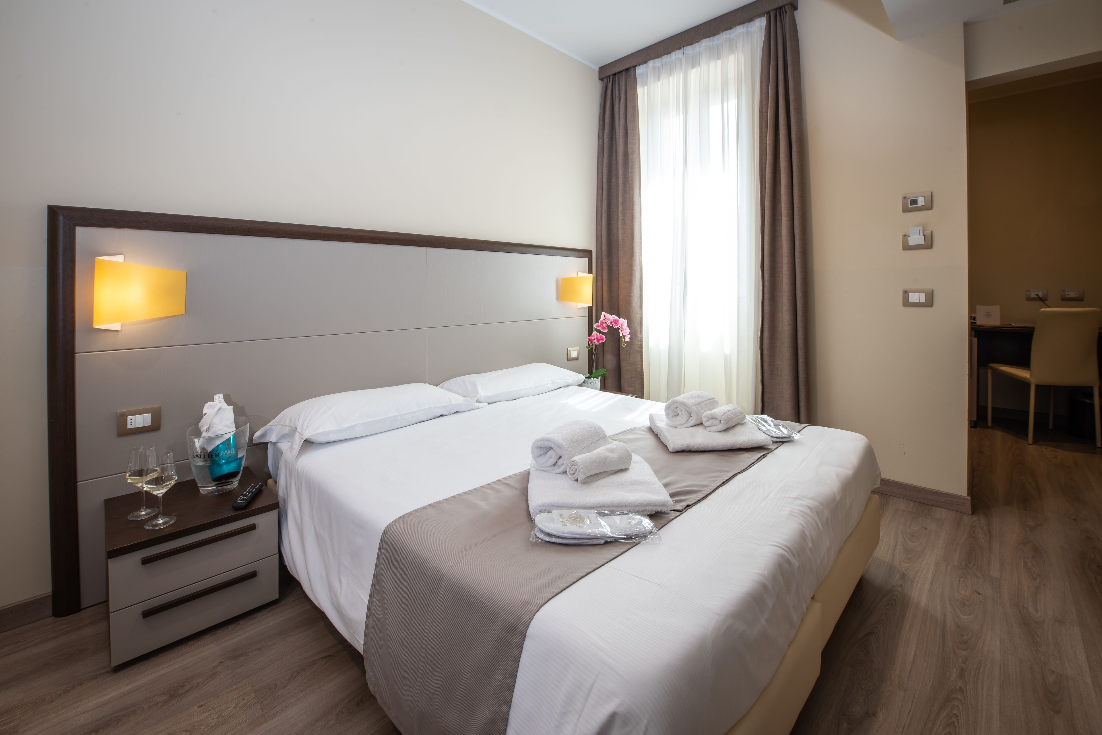 A hotel room with a large bed, bedside tables, and a desk.