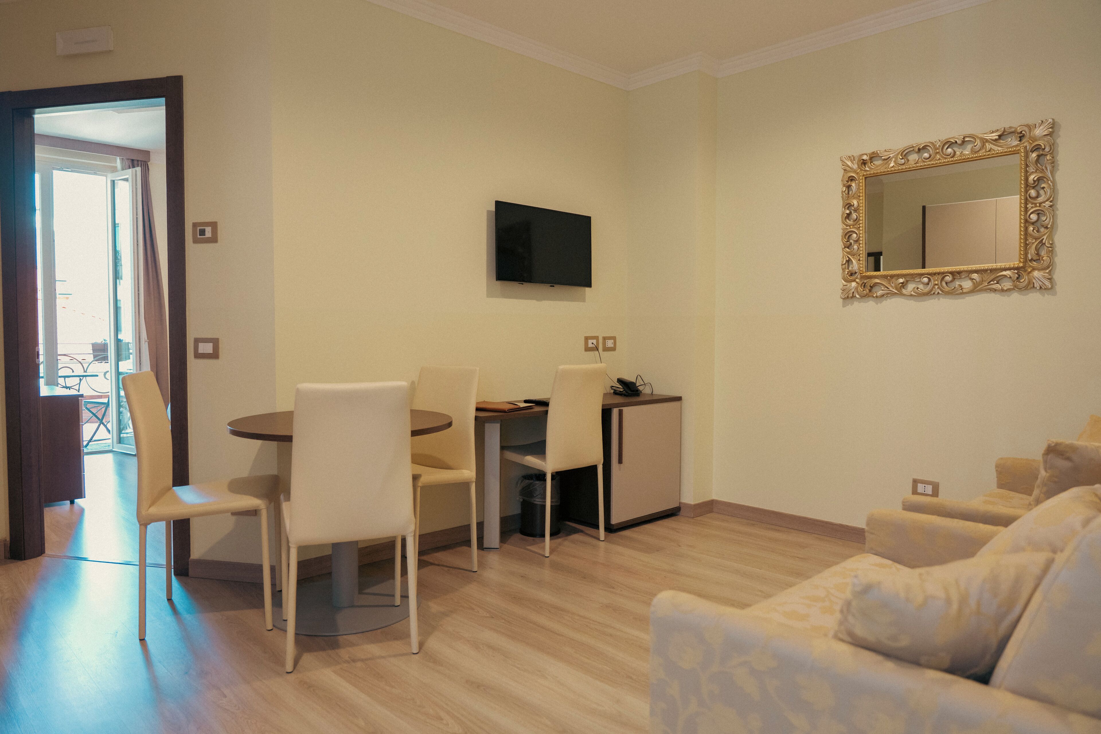 Una sala de estar con sofá, televisor montado en la pared y comedor con sillas y mesa.