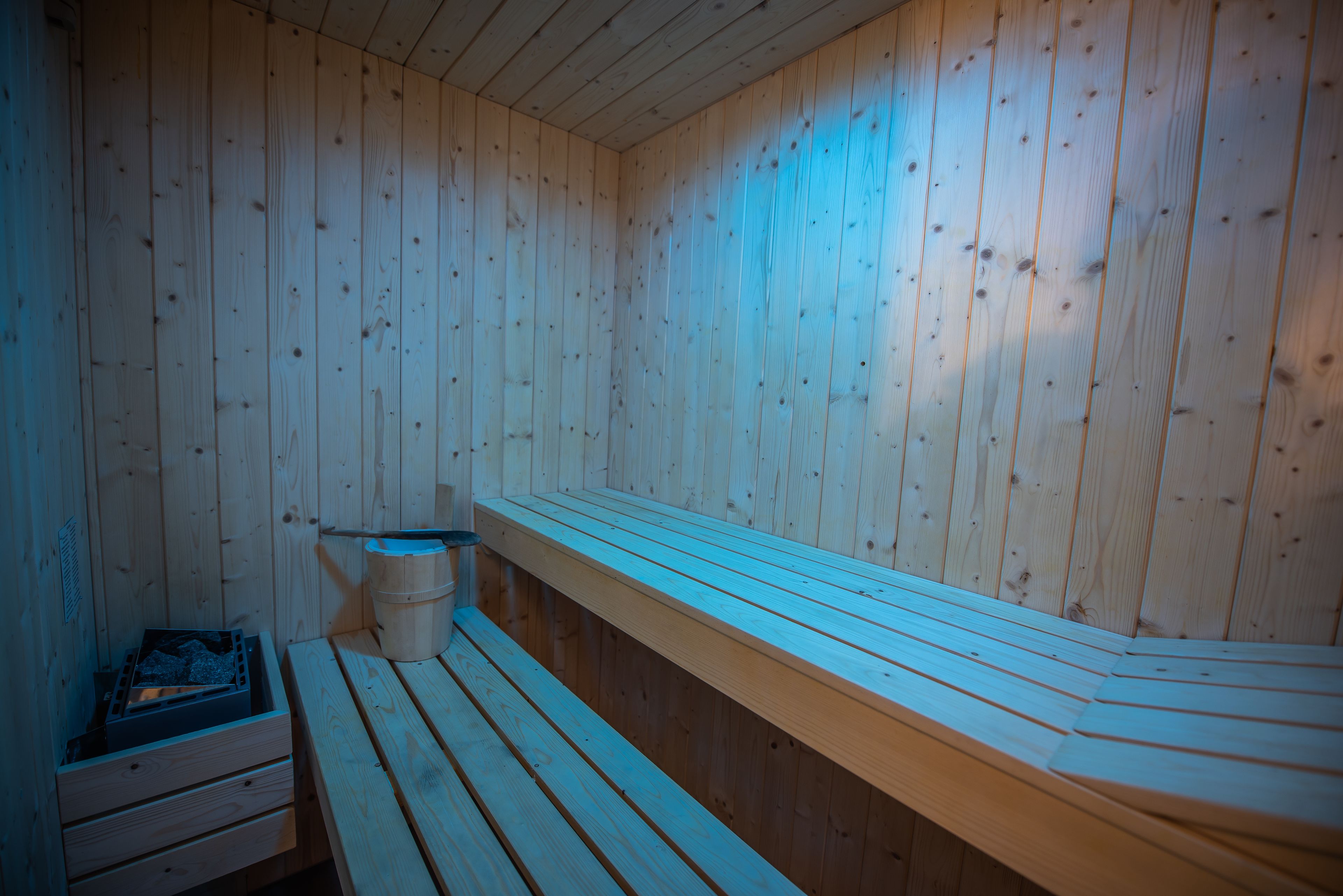 A sauna with wooden benches and a wooden wall.