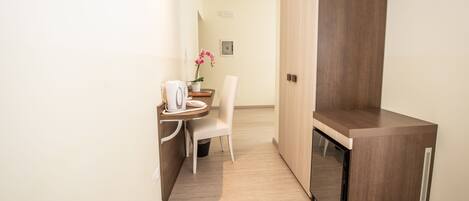 A compact kitchenette with a coffee maker, a chair, and a small table.