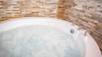 Una vasca da bagno con parete rivestita in mosaico di pietra.