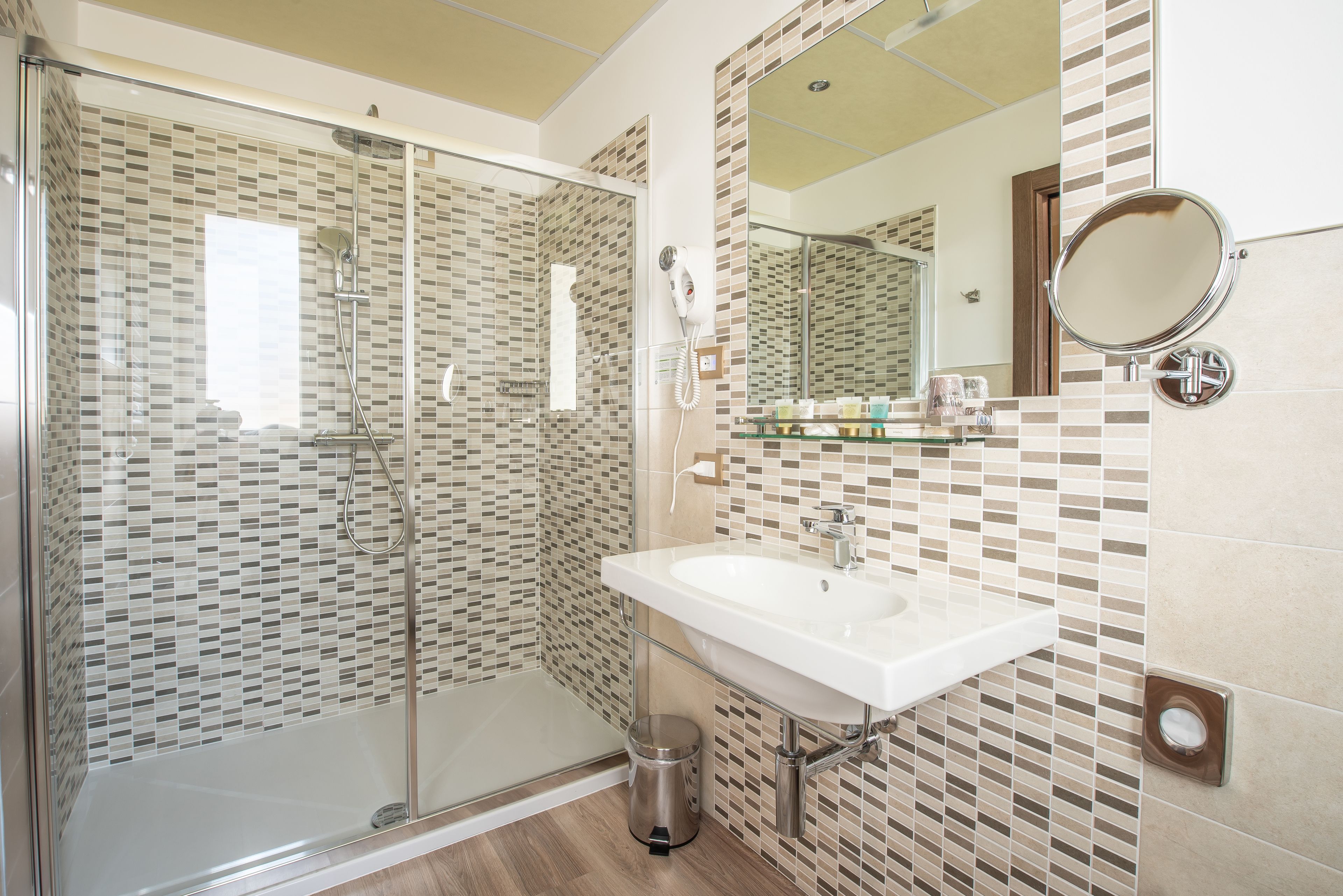 A modern bathroom with a glass-enclosed shower, a white sink, and a tiled backsplash.
