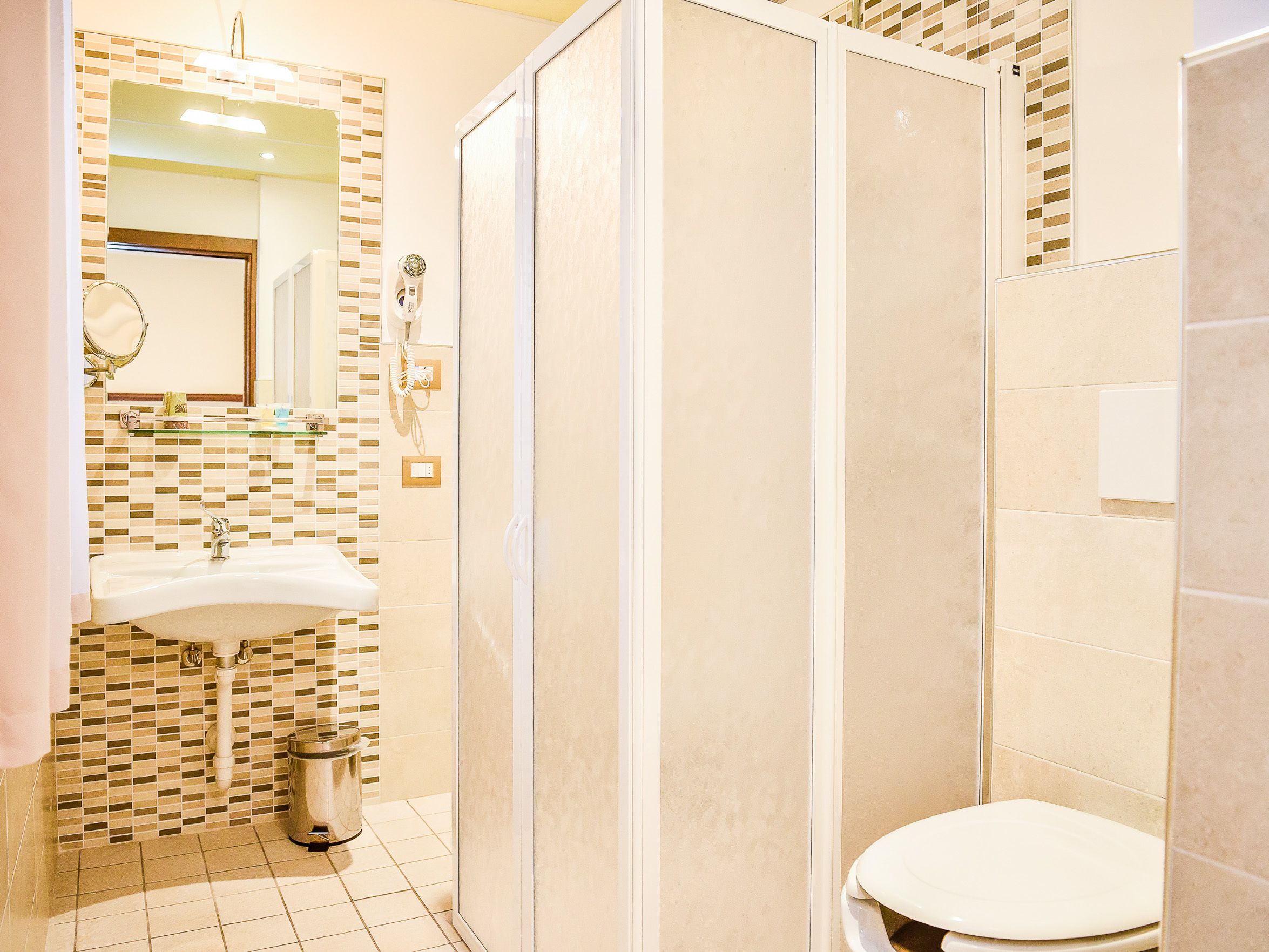 Un baño con lavamanos, espejo e inodoro.