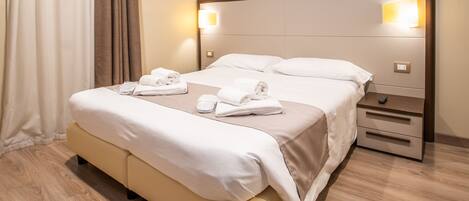 Una habitación de hotel con cama, mesitas de noche y un pequeño escritorio.