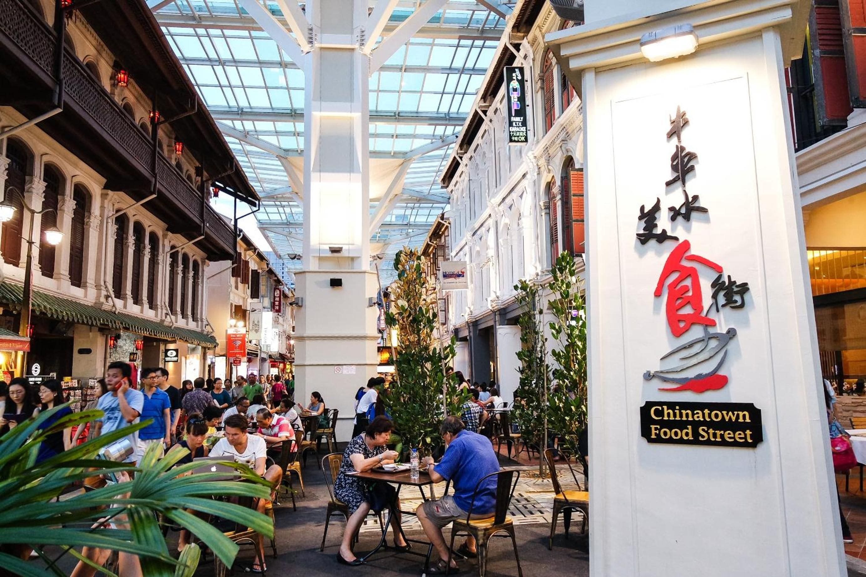A bustling indoor food court with multiple dining tables and people.