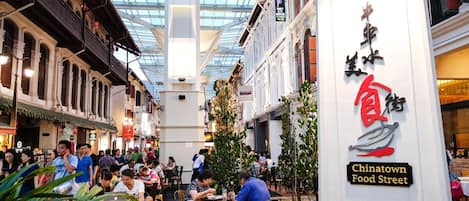 A bustling indoor food court with multiple dining tables and people.