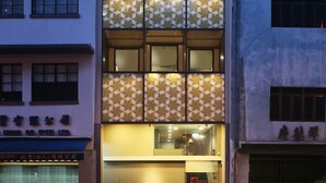 Un edificio de varios pisos con fachada decorativa, una entrada visible con puerta de vidrio y un letrero con caracteres chinos.
