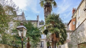 A pathway with steps leading to a building, surrounded by greenery and palm trees. - Villa Victor Louis (Bordeaux)