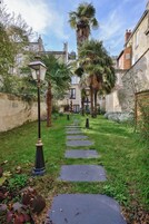 Un sendero con escalones que conduce a un edificio, rodeado de follaje y palmeras.