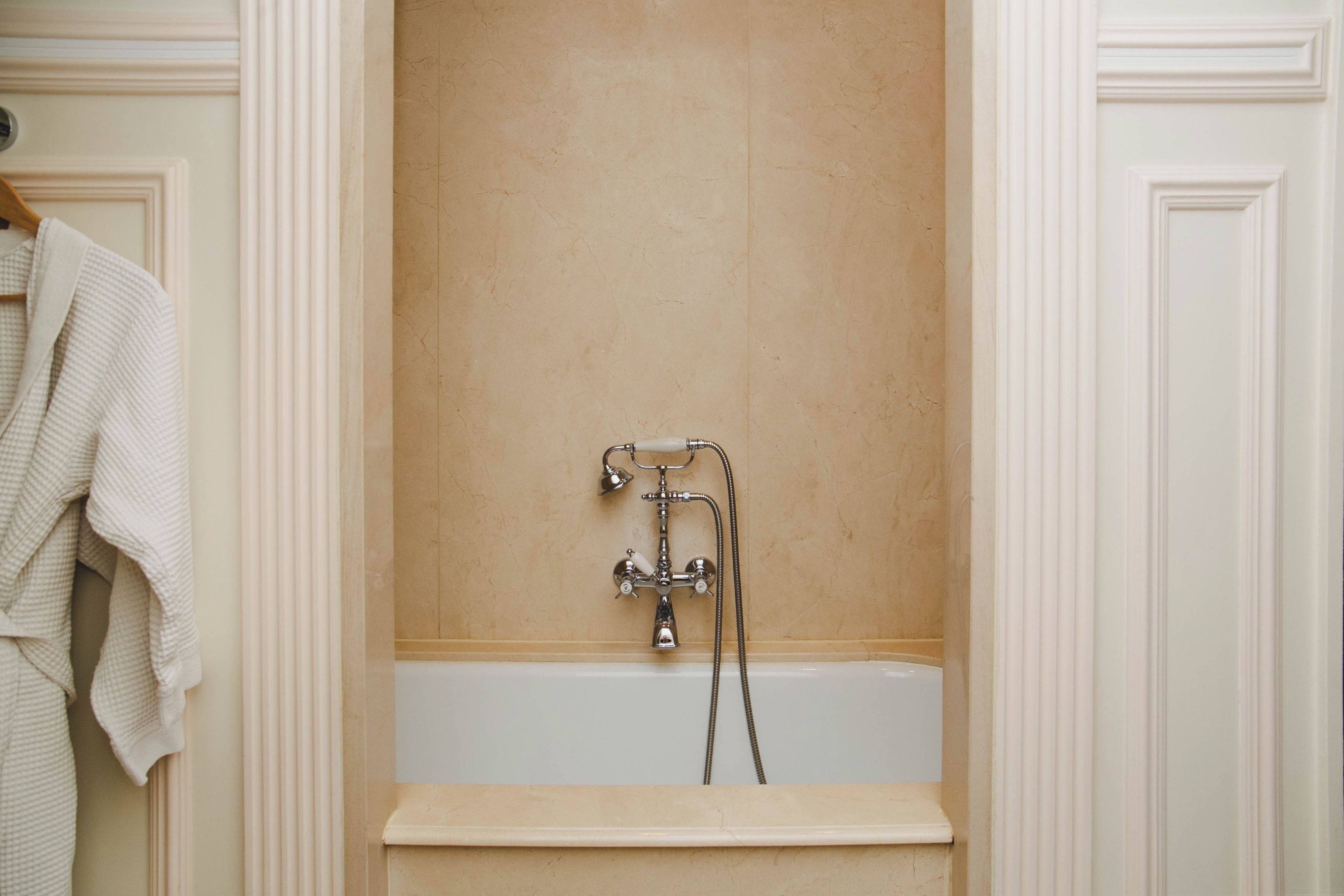 A bathroom with a bathtub, a shower, and a towel rack.