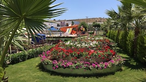 Un jardin aménagé avec un toboggan aquatique, des palmiers et des parterres de fleurs.
