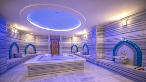 A modern spa room with a central hot tub, marble flooring, and decorative wall sconces. - Babillon Hotel Spa & Restaurant (Iyidere)