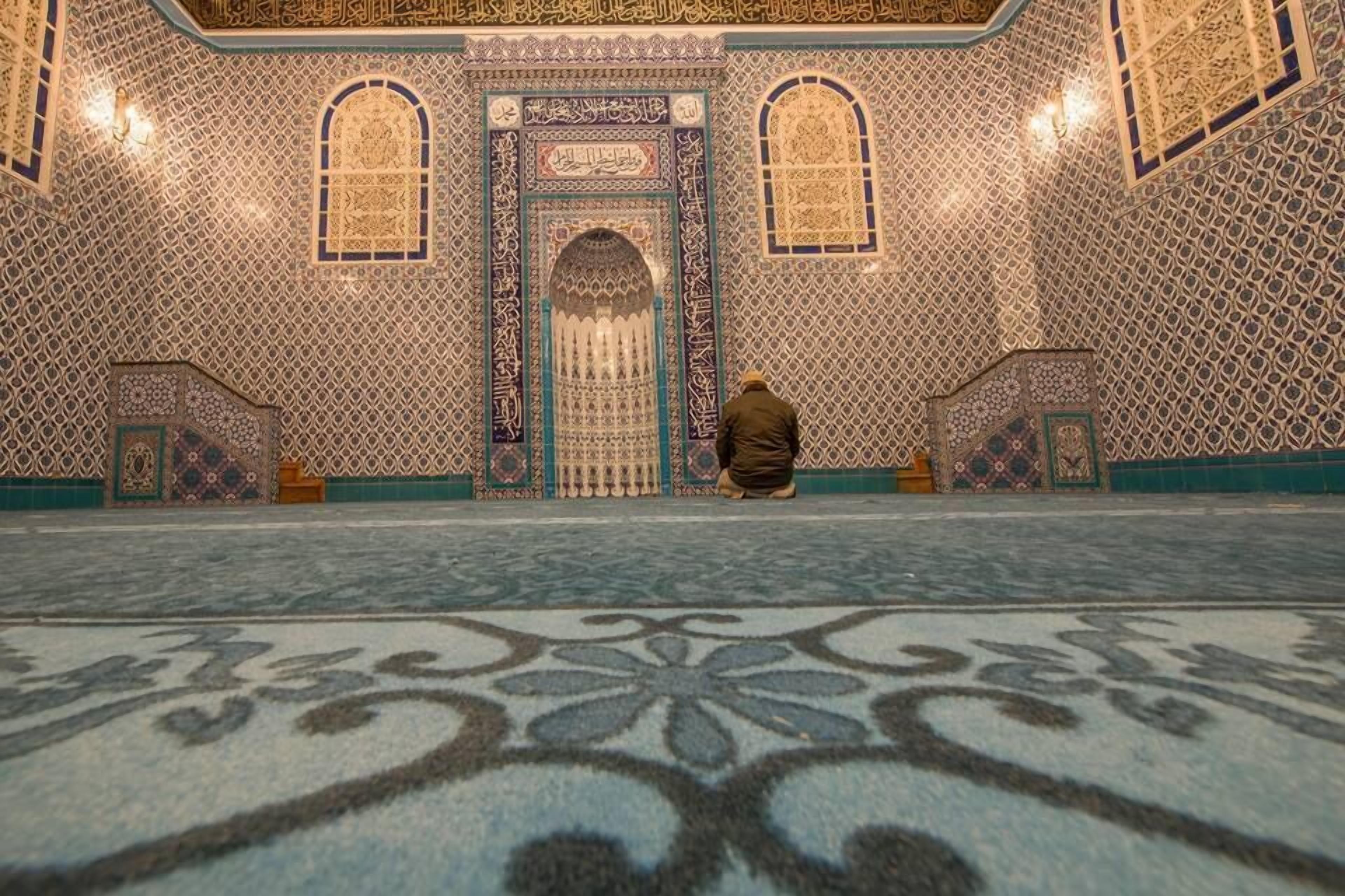 An interior with intricate tile patterns, a central door, and a person seated in the foreground.