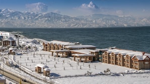 A snow-covered resort with multiple buildings, a beach, and mountains in the background. - Babillon Hotel Spa & Restaurant (Iyidere)