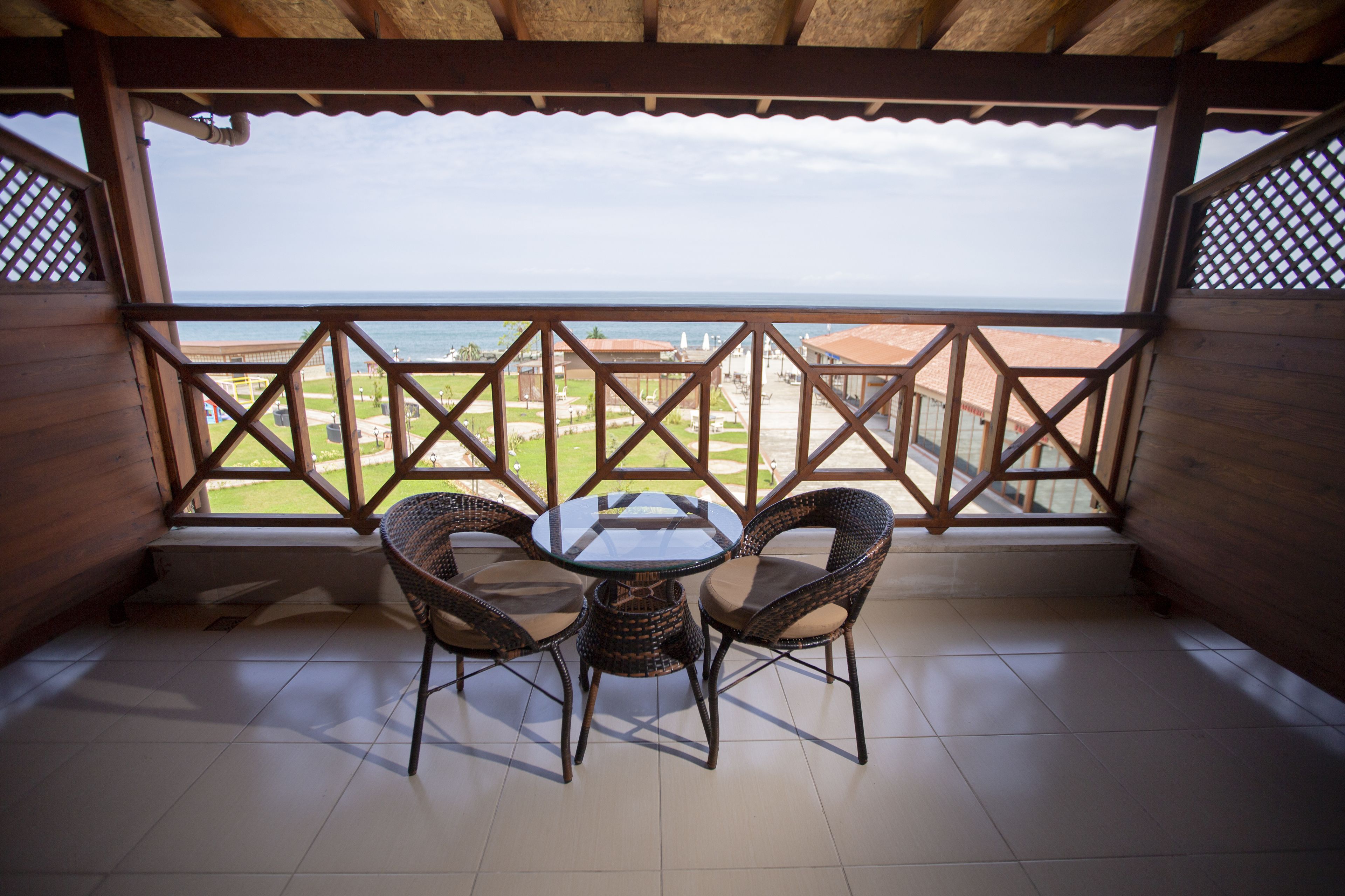 Área de estar coberta ao ar livre, com mesa e cadeiras, oferecendo vista para edifícios e um corpo d'água.
