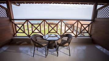 Área de estar coberta ao ar livre, com mesa e cadeiras, oferecendo vista para edifícios e um corpo d'água.