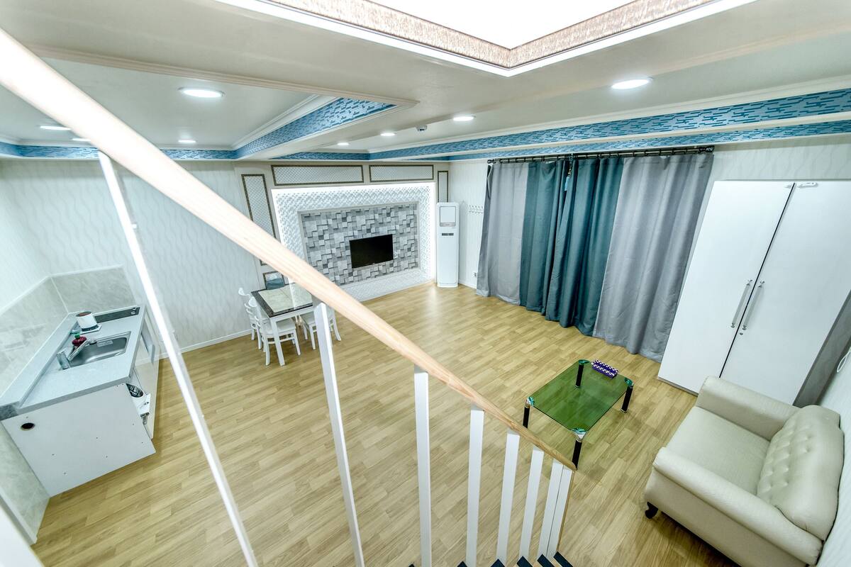 A modern living room with a fireplace, a dining area, and a staircase.