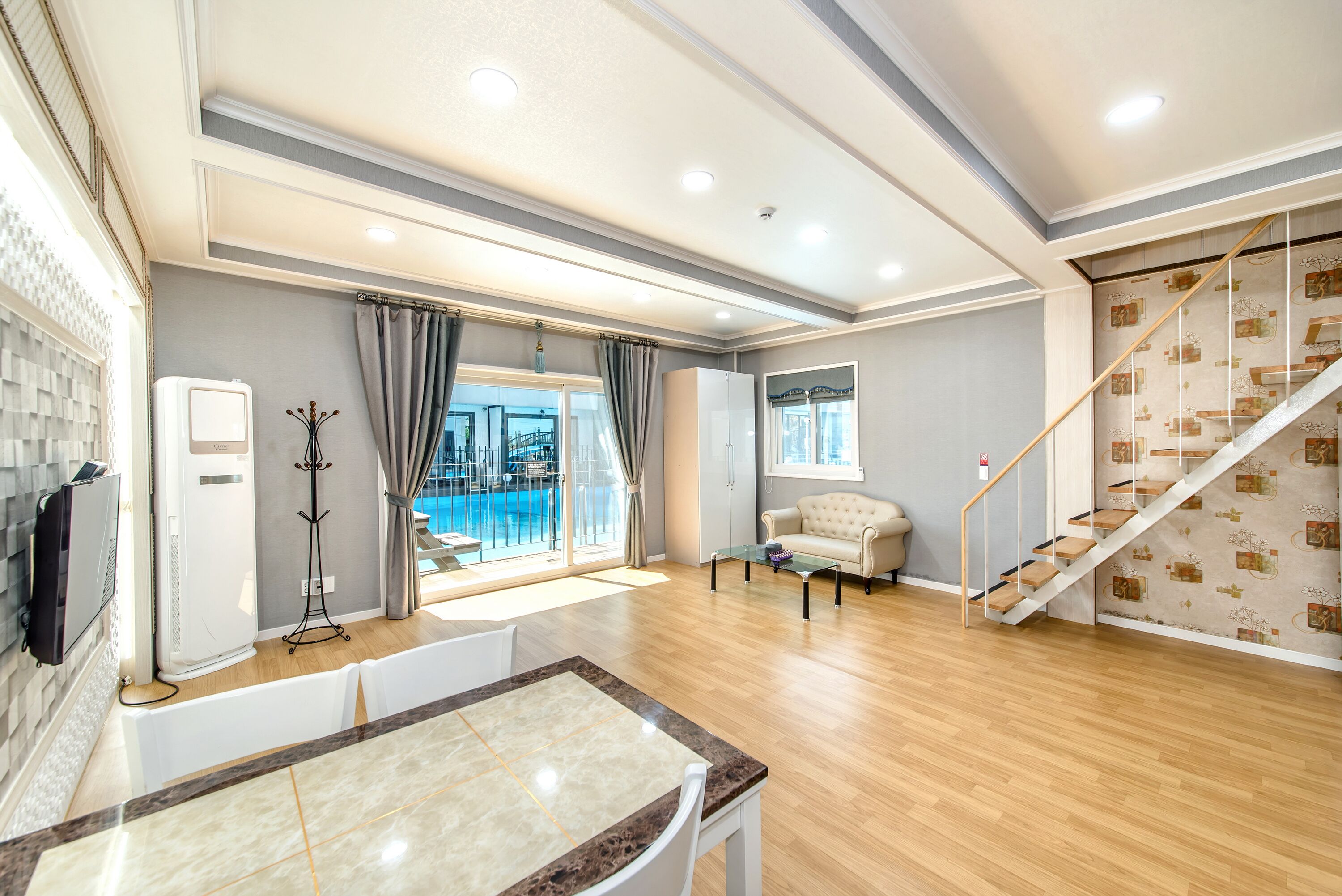 Amplia sala de estar con piso de madera, una mesa de comedor, un sofá y una escalera.