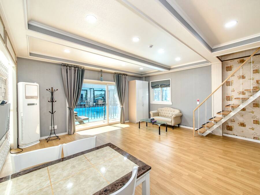 Amplia sala de estar con piso de madera, una mesa de comedor, un sofá y una escalera.