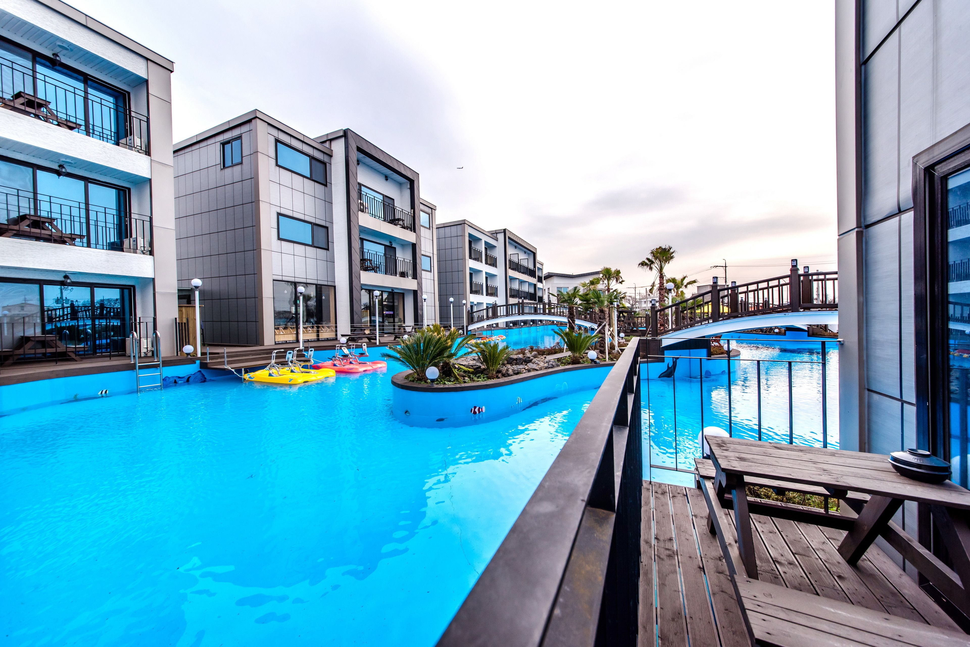 A modern hotel with a swimming pool, wooden deck, and balconies.