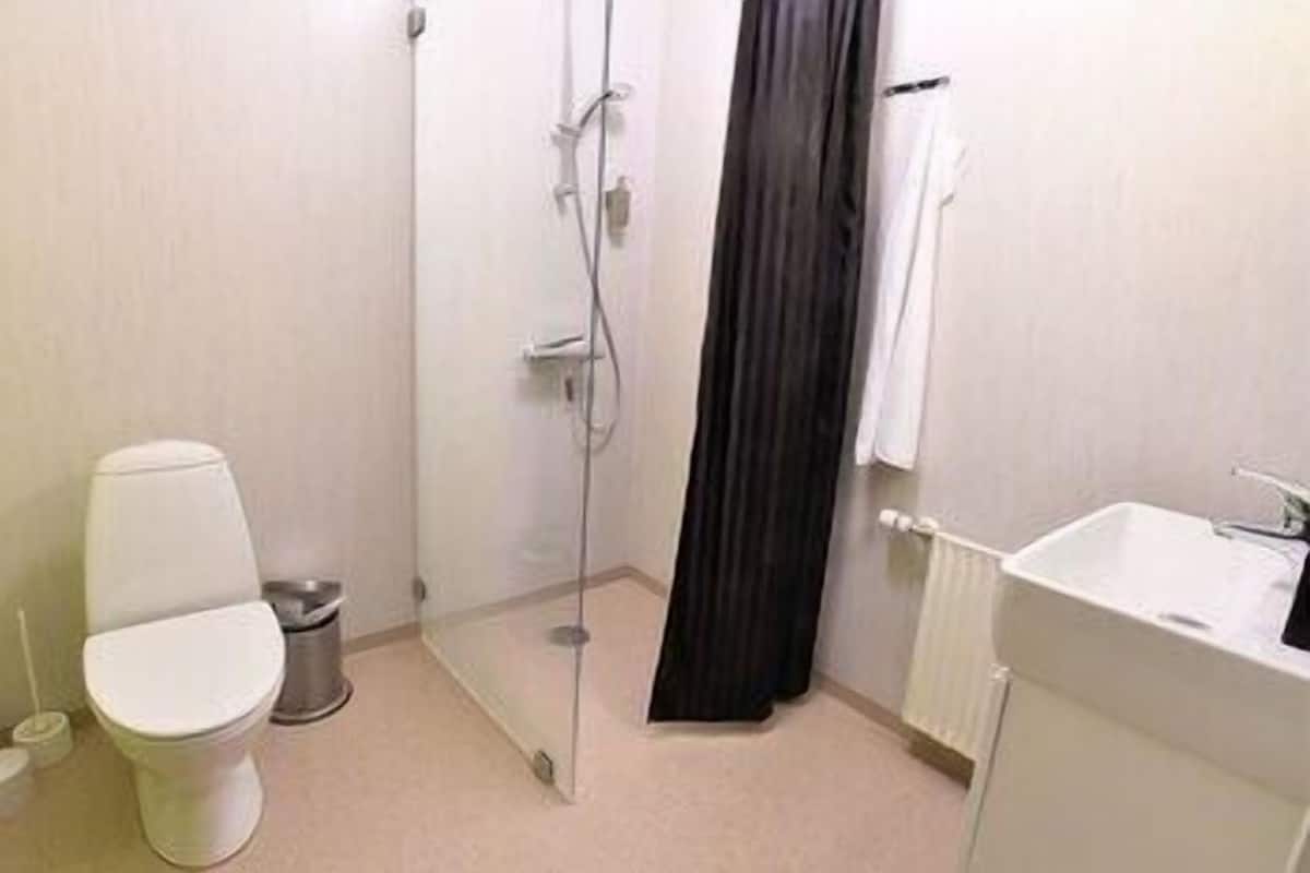 A bathroom with a toilet, shower, and sink.