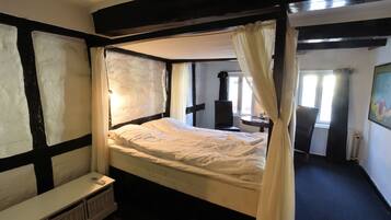 A four-poster bed with a canopy, a bedside table, and a small window.