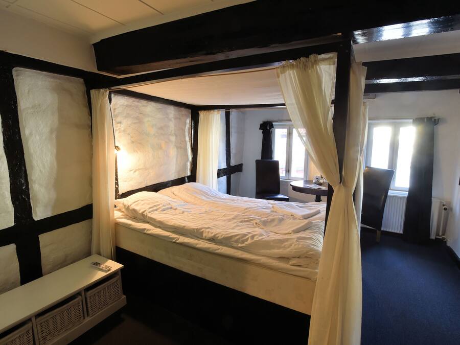 A four-poster bed with a canopy, a bedside table, and a small window.