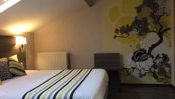 A hotel room with a bed, a desk, a radiator, and a wall with a floral mural.