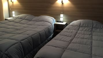 A hotel room with two beds, a wooden headboard, bedside lamps, and a nightstand with a phone.