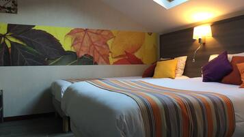 Quarto com claraboia, cama com roupa de cama listrada e um mural de folhas de outono.