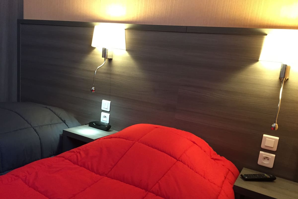 Une chambre d’hôtel avec un lit, une table de chevet, une lampe et une télécommande.