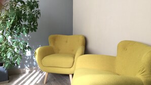 Une pièce avec un fauteuil jaune et une plante en pot.