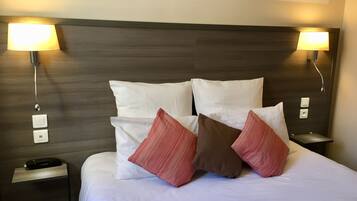A hotel room with a large bed, two bedside lamps, a nightstand, and a painting on the wall.