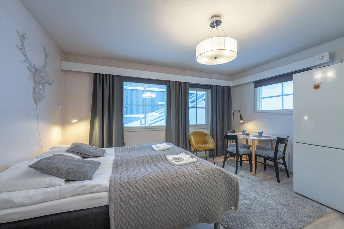 Hotelkamer met een bed, een bureau, een stoel, een koelkast en uitzicht op een gebouw.