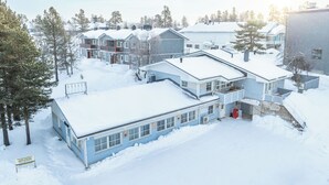 Zona residencial com várias casas cobertas de neve, cercada por árvores.