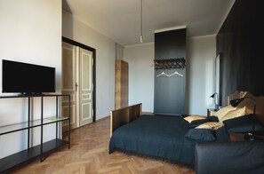 A modern bedroom with a bed, a TV on a stand, a wardrobe, and a hanging clothes rack. - Boutique Apartments - Main Market Square (Kraków)