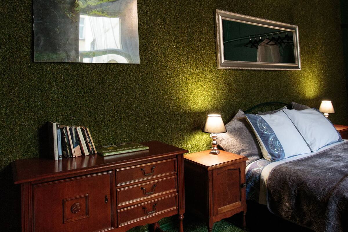 A bedroom with a bed, nightstands, a dresser, and two wall-mounted lamps.