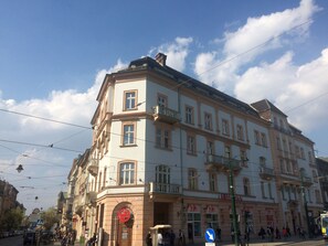 A multi-story building with a classical architectural style, featuring a prominent entrance with a sign, multiple windows, and balconies. - Boutique Apartments - Main Market Square (Kraków)