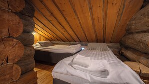 Un dormitorio tipo cabaña de madera con dos camas, paredes de madera y techo inclinado.