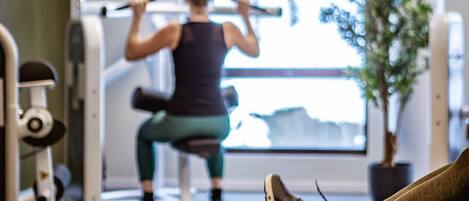 Un gimnasio con equipo de ejercicio, un ventanal grande y una planta en maceta.