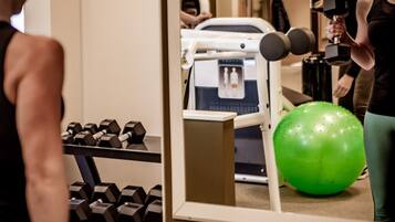 Un gimnasio con equipo de ejercicio, incluyendo mancuernas y una pelota de ejercicio verde.