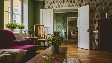 A cozy living room with a wooden floor, a red armchair, a wooden coffee table, and a green plant.